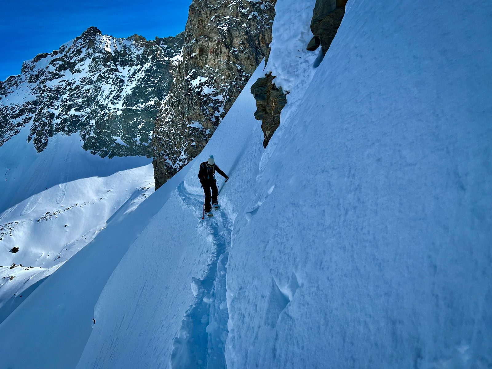Claudia in einer steilen Schneeflanke unter Felsen