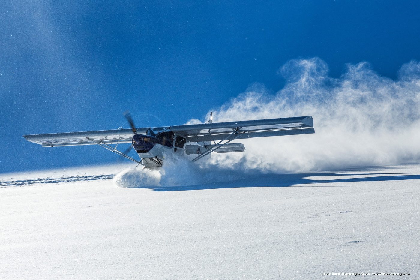 Leichtflugzeug im Schnee, dahinter Berge